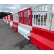 Long line of crash-tested Defender50 barriers with interlocking red and white plastic fencing, ideal for road safety and event management.
