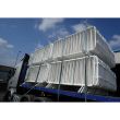White barriers loaded onto a flatbed truck, stacked and secured with straps, ready for transport under a blue sky.