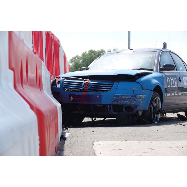 Severe front-end collision test with blue vehicle demonstrating high-impact durability of Defender50 water-filled barrier.