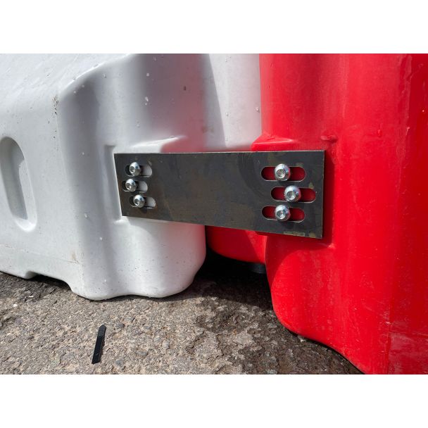 Close-up of heavy-duty steel linking plate securely bolting together red and white Defender50 crash-rated barriers for maximum stability.
