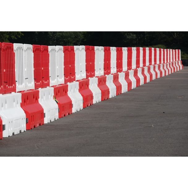 Wide shot of Defender50 crash-tested water-filled barriers installed in an alternating red and white pattern, forming a long continuous safety wall.