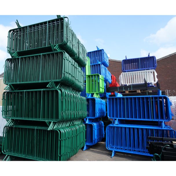Tall vertical stacks of green, blue, red, and white barriers outside a warehouse building.