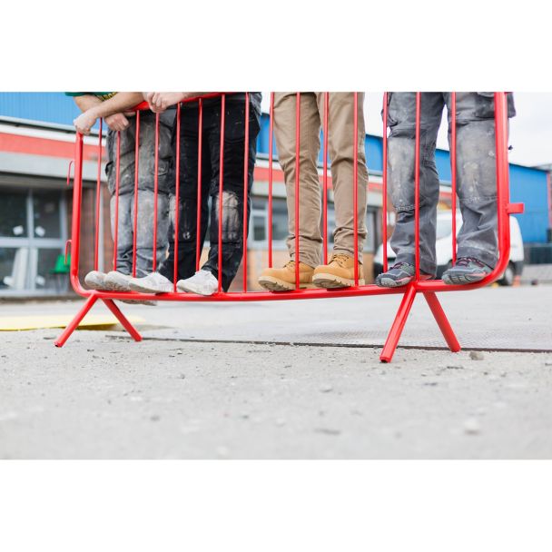 Ground-level photo illustrating how the barrier supports the weight of multiple people standing on its lower rail.